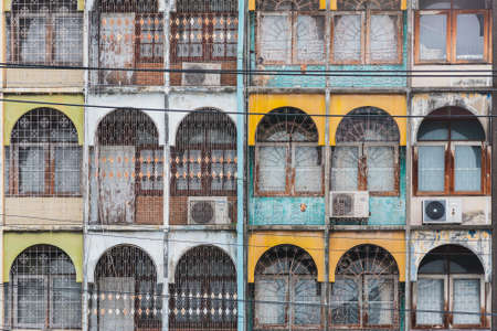 Bangkok - September 8, 2018: front of regular old Thai prefabricated apartment building. Rows of arches, tiny balconies, bars, ACs; Clumsy but somehow cozy architecture is often demolished these days.のeditorial素材