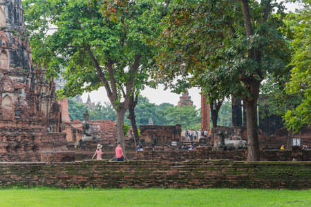 Ayutthaya, Thailand - September 2, 2018: brick ruins of an ancient Buddhist temple Wat Phra Mahathat (Mahatat) with trees, Buddhas and visitors.のeditorial素材