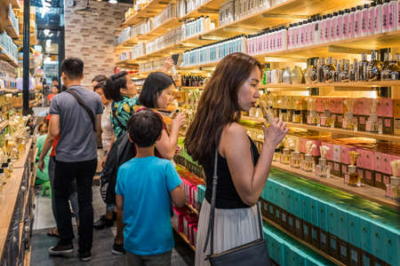 Bangkok, Thailand - May 13, 2018: women smell fragrance oils standing along shelves filled with long rows of bottles with aromas in a shop of the smells at Chatuchak Weekend Market.のeditorial素材