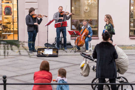 Saint Petersburg, Russia - August 22, 2020: a violinist stares at a young woman passing by while playing violin together with a street musical band in Andreevsky Boulevard on Vasilyevsky Island.のeditorial素材