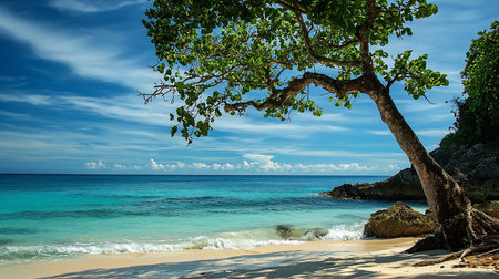 A serene tropical beach scene with turquoise water, white sand, and a lush tree providing shade. Waves gently lap the shore under a bright blue sky with scattered clouds.の素材