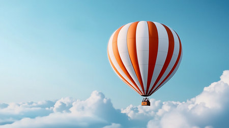 A vibrant orange and white striped hot air balloon floats gracefully above a sea of fluffy white clouds, set against a clear, bright blue sky, creating a serene and uplifting scene.の素材
