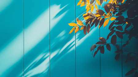A striking image featuring golden leaves and their shadows cast against a vibrant teal wall. The composition is minimalist, emphasizing the contrast between light and shadow.の素材