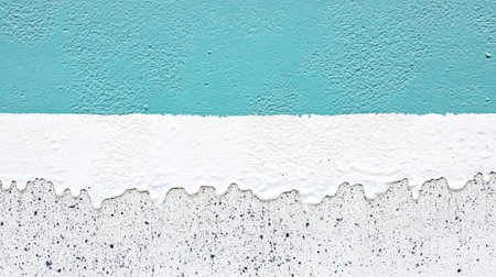 A close-up view of a textured concrete surface with horizontal bands of teal and white paint, featuring dripping white paint along the bottom edge.の素材