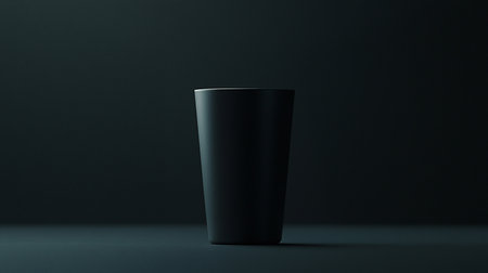 A sleek, matte black tall tumbler cup stands in a dark, moody setting, showcasing its smooth texture and clean lines.の素材