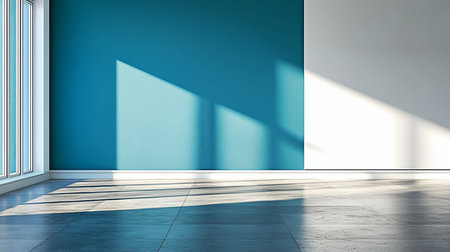 An empty room with a textured teal wall and a white wall, illuminated by sunlight casting geometric shadows on the floor.の素材