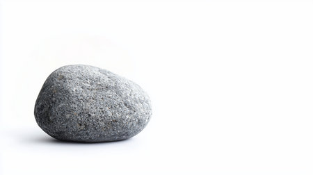 A single, smooth, grey, oval-shaped stone with a speckled granular texture rests on a clean white surface.の素材