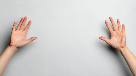 A pair of human hands, left and right, shown with open palms facing forward. The fingers are gently spread apart in a symmetrical pose, as if framing an empty space.の素材