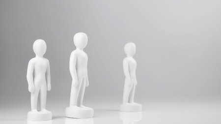 Three identical white figurines stand in a row. Each figure has a minimalist human form, smooth surface, and a rounded base.の素材