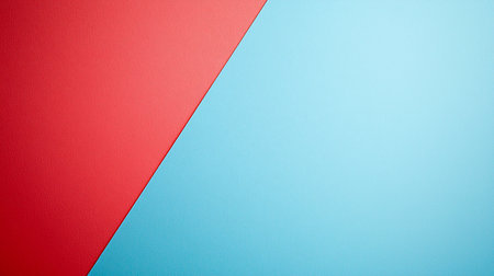 A minimalist background of two colored paper sheets, vibrant red and light blue, arranged to form a diagonal division with a subtle texture.の素材