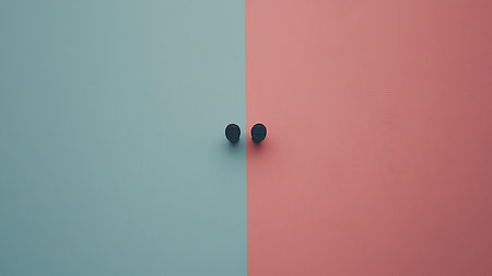 Two dark, round, button-like objects centered on a textured wall, split vertically into vibrant teal and soft pink sections.の素材