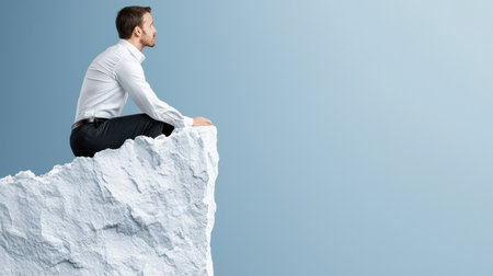 Young man sitting on rocky cliff edgeの素材