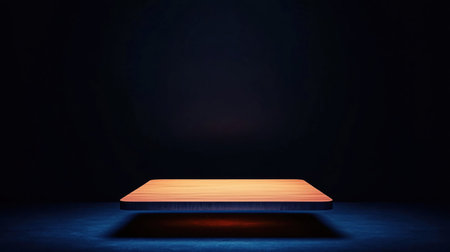 A wooden table is illuminated in a dark room, creating a minimalist and mysterious atmosphere. The black background enhances the focus on the table.の素材