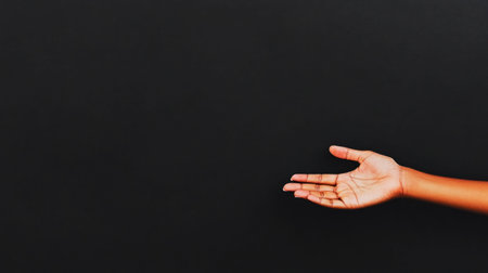 A close-up shot of a hand with an open palm, set against a black backdrop, suggesting an offer or presentation.の素材