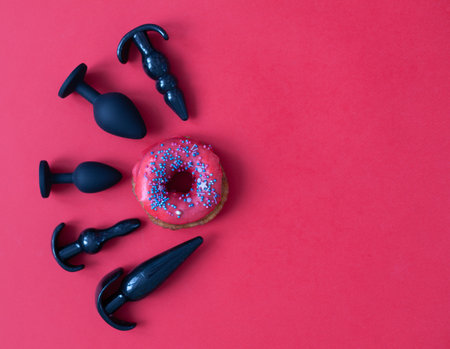 Black silicone sex toys on a red background. Erotic toy for fun. Diffrent anal butt plugs. View from above with space for textの写真素材
