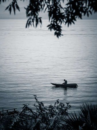 Small rowing boat with single fisherman on lake
