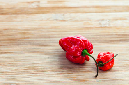 fiery red komodo dragon chillies on a wooden backgroundの写真素材
