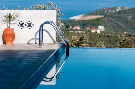 Grab bar ladder leading into blue infinate pool on the island of Skiathos, Greeceの写真素材