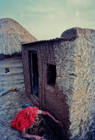 04 Mar 2020 woman applying Mud and cow dung plaster on house wall Sri Dungargarh Bikaner District Rajasthan Indiaのeditorial素材
