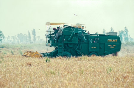 03 04 2019 Farmers in a harvesting machine in a wheat field Punjab India.のeditorial素材