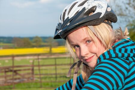Close up of a pretty young blonde girl wearing a cycle helmet in a rural settingの写真素材