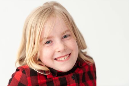 Close up of a smiling young blonde preteen girl on a white studio background
