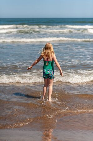 Young blonde girl paddling in the sea on a sunny dayの写真素材