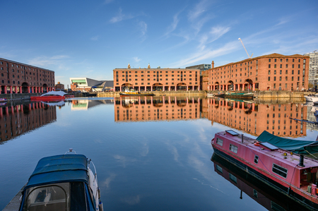 Wide shot of the Albert Dock in Liverpool and the museum of Liverpool. Boats moored in the foreground on the still water and the Liver Birds just visible above the roof tops.のeditorial素材