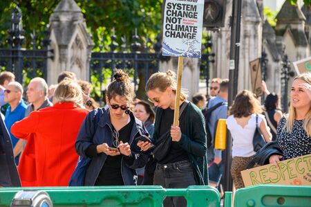 LONDON - SEPTEMBER 20, 2019: Climate Change protesters using smartphones and holding protest placards at an Extinction Rebellion demonstrationのeditorial素材