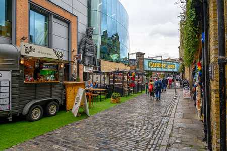 LONDON - SEPTEMBER 30, 2019: A cobbled street in Camden Market with a modern glass building and the...