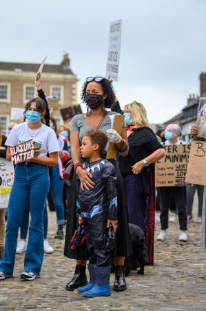 Richmond, North Yorkshire, UK - June 14, 2020: A protester wears a Black Lives Matter PPE face mask and hugs her Superhero son on the cobbles of The Marketplace at a BLM protest in Richmond, North Yorkshireのeditorial素材