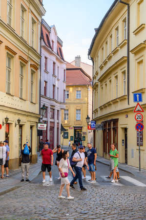 PRAGUE - JULY 20, 2019: Tourists crossing a zebra crossing on an old cobbled street in Prague, Czech Republicのeditorial素材
