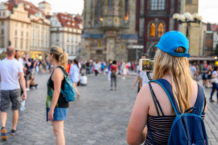 PRAGUE - JULY 20, 2019: A young female tourist uses a smartphone to video The Old Town Square, Prague, Czech Republicのeditorial素材