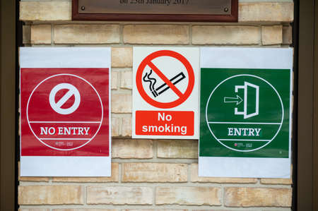 LONDON - SEPTEMBER 12, 2020: Covid 19 social distancing warning signs alongside a No Smoking sign on...