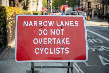 LONDON - SEPTEMBER 14, 2020: Narrow lanes road traffic sign protecting cyclists, with traffic out of...