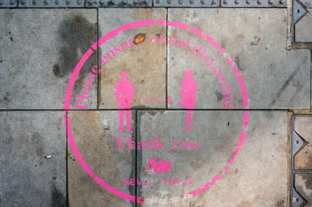 LONDON - NOVEMBER 3, 2020: An overhead shot of a pink Covid 19 social distancing sign painted on the...