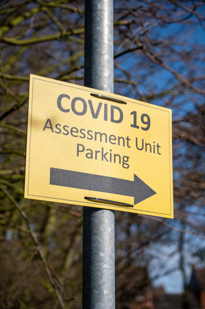 Amble, Northumberland, UK - March 21, 2021: Yellow Covid 19 Assessment Unit Parking sign. Portrait orientation.のeditorial素材