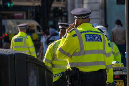 LONDON - MAY 29, 2021: British police officer in a high visibility jacket uses a mobile cell phoneのeditorial素材