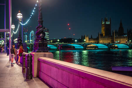 LONDON - SEPTEMBER 14, 2021: Colourfully lit night scene on The Queen's Walk, Southbank outside County Hall. Westminster Bridge and The Houses of Parliament in the background.のeditorial素材