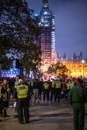 LONDON - NOVEMBER 5, 2021: A line of Police officers in Parliament Square during The Million Mask March. Houses of Parliament in the background.のeditorial素材