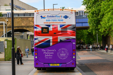 LONDON - May 18, 2022: Back of a London Tour Bus decorated for the Queen's Platinum Jubilee celebrations in London with train passing in the backgroundのeditorial素材