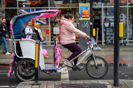 LONDON - May 20, 2022: Woman wearing pink coat while riding rickshaw on London Streetのeditorial素材