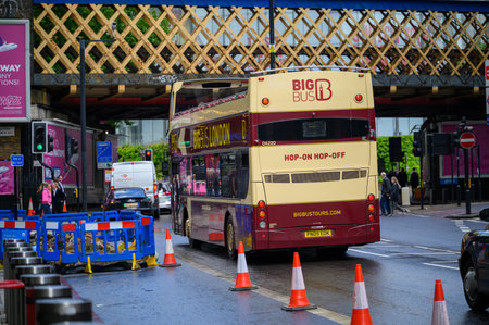 LONDON - May 20, 2022: Open top London Double Decker Tour Bus in road works beneath rail bridge outside Waterloo Stationのeditorial素材