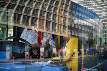 LONDON - May 20, 2022: Passengers talk to driver of London Double Decker bus. Viewed through reflections of buildings and busy streetのeditorial素材