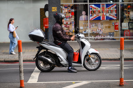 LONDON - May 20, 2022: Man in helmet on white motor scooter stopped on roadのeditorial素材
