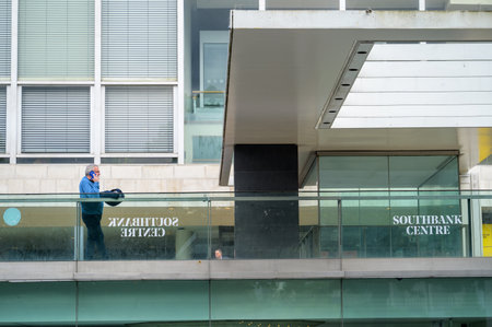 LONDON - May 20, 2022: Man uses mobile phone while leaning on railings outside the South Bank Centreのeditorial素材
