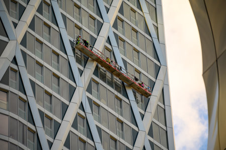 LONDON - November 4, 2020: Men work from suspended platform on side of skyscraper in London Docklandsのeditorial素材