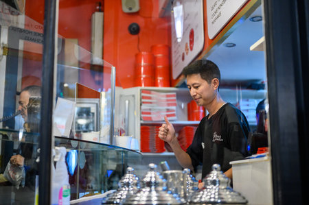 LONDON - November 12, 2022: Get a behind-the-scenes look at a cookie store with this view of a man at work through the shop window, preparing delicious treats for customers.のeditorial素材