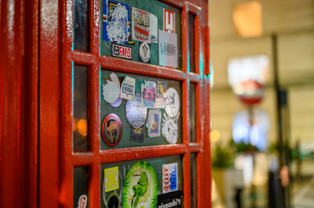 LONDON - April 21, 2023: Experience the vintage charm of London's traditional phone box covered in a plethora of unique stickers, captured in a stunning close-up shot.のeditorial素材