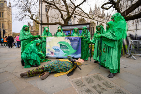 LONDON - April 22, 2023: Green Spirits at XR march in London, posing with a protest banner outside Westminster Abbey and Houses of Parliament in Parliament Square, advocating for environmental justiceのeditorial素材